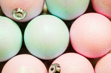 Close-up of pastel, pink, and blue Christmas balls. Textured background