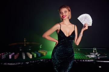 Photo of chic woman in glamour dress hold her profit from poker game fortune roulette over green...