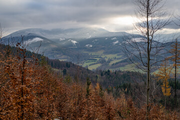 Cloudy sky with hills in the background and snow.
