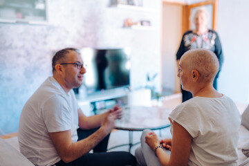 Woman with cancer. Three individuals engaged in a group discussion, emphasizing the importance of emotional support and connection across relationships in a cozy living setting.