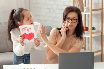 Teen girl giving greeting card to her busy mother, irritated mom not paying attention, taking...