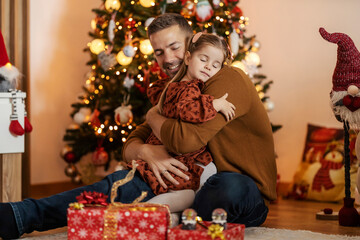 Happy dad hugging his little girl and spreading love on christmas eve at home.