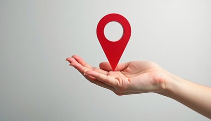 Hand holds red navigation pin. Simple design for location finding. Illustrates concept of direction. Clean studio shot. Modern feel. Easy to use for digital maps app. Helpful for navigation. Suitable