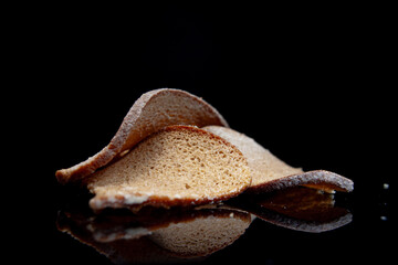 Crunchy dessert pieces arranged on a reflective surface with dramatic lighting