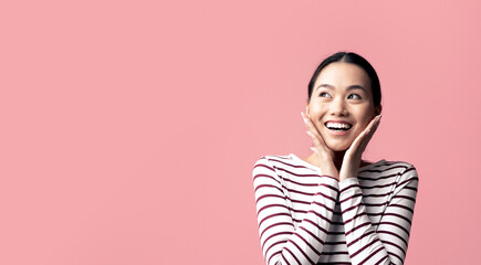 Portrait Of Surprised Young Asian Woman Touching Face And Looking At Copy Space With Excitement, Amazed Korean Lady Emotionally Reacting To Good News Or Nice Offer, Standing On Pink Background