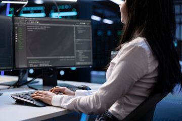 Close up shot of software developer in data center typing on keyboard, working on computer to do...