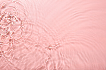 Rippled surface of clear water on pink background, top view