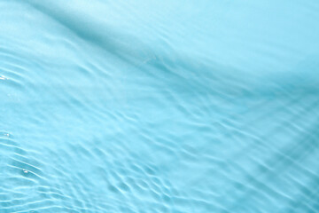 Rippled surface of clear water on light blue background, top view