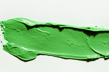 Green paint is being applied to white surface. White and green background with cream. Close up a smear of white cream on a background of green. Close up of a green smear of cream on a white lifestyle.