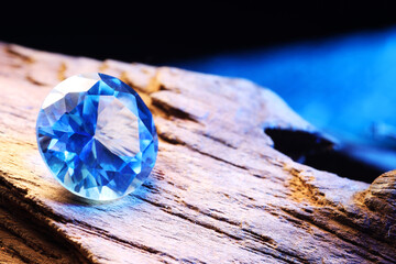 Beautiful shiny light blue gemstone on stone against dark background, closeup