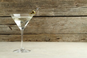 Martini cocktail with olives in glass on light table, space for text