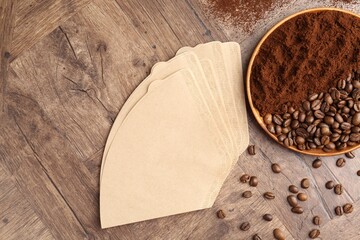 Paper filters, coffee beans and ground on wooden table, flat lay