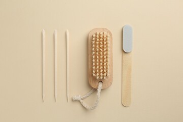 Set of pedicure tools and flowers on beige background, flat lay