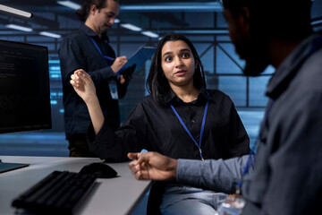 Teamworking programmers in data center using diagnostic tools and system monitoring software to identify root cause of errors. Multiethnic team in server farm repairing equipment together