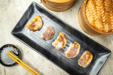 Fried chinese dim sum dumpling, gyoza, jiaozi or mandu in the plate with chopsticks and soy sauce on the table. Food for breakfast, lunch or dinner