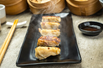 Fried chinese dim sum dumpling, gyoza, jiaozi or mandu in the plate with chopsticks and soy sauce...