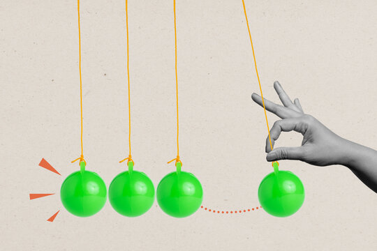 A human hand pulling a balancing ball on a pendulum on a colored background