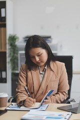 Charming asian businesswoman sitting working on laptop in office.