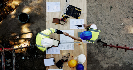 Blueprint, construction and men at table with handshake, collaboration and inspection agreement...