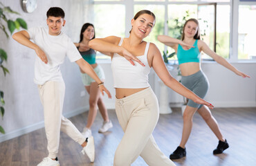 Obraz premium Energetic sporty young girl practicing modern vigorous dance movements in group dance class ..