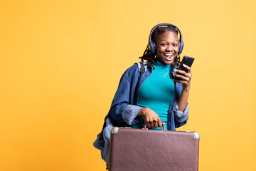 Portrait of overjoyed teenager reading messages on phone, receiving good news while travelling with...