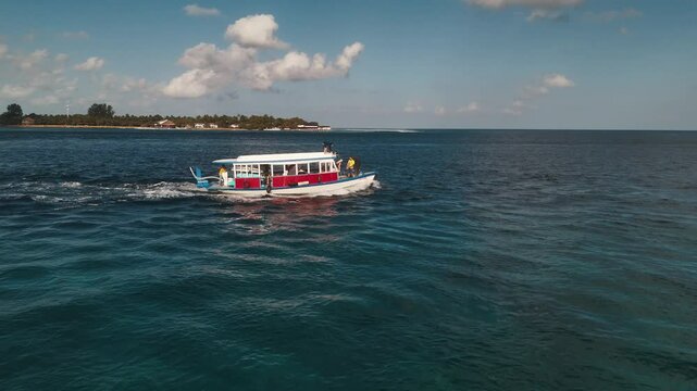 Surfing boat with surfers. Boat moves in the ocean with surfers on board ready to jump into the water