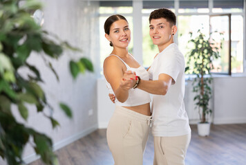 Young guy and young woman dancing pair dance in dance studio