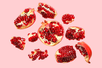 Flying fresh pomegranates on pink background