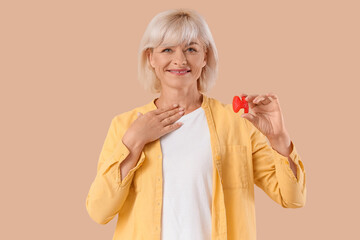 Mature woman with thyroid gland model on beige background