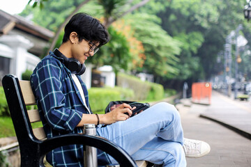Obraz premium Young Man Using Digital Tablet on a Bench of The Urban Sidewalk