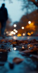 A blurred figure walks past wet autumn leaves at dusk.
