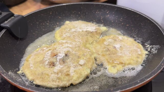 Umbrella mushrooms are frying in batter in the frying pan. Close-up.