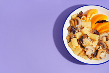 Plate with delicious Italian pasta salad on violet background with space for text