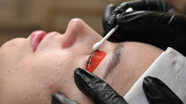 Caucasian woman undergoing eyelash lamination procedure. 