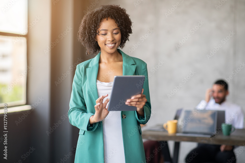 Poster a professional woman in business attire smiles while using a tablet. in the background, a man engage