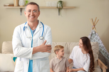 Male pediatrician against mother with her little son at home