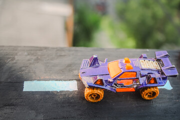 Toy monster cars placed on wooden blocks with a highway design, miniature concept that blends in with nature, still life photography. © FalOpang