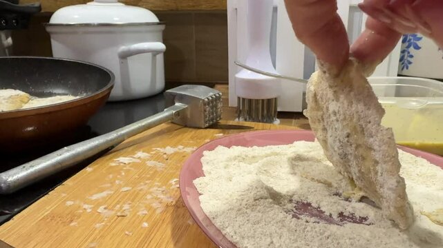 A woman dips the mushroom in batter, then in flour, and places it in the frying pan. She is frying mottled umbrella mushrooms.