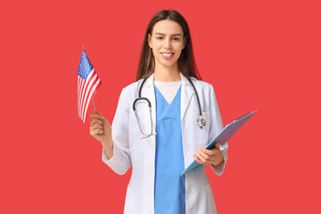 Young female doctor with USA flag and clipboard on red background