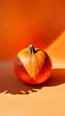 A whole ripe pumpkin on an orange background on the edge.