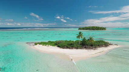 Aerial view of a woman enjoying a tropical paradise as she walks on a sandbank that connects a...