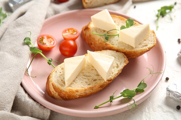 Plate with bread, triangles of tasty processed cheese, tomatoes and micro green on light table, closeup