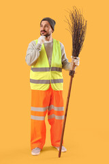 Thoughtful male scavenger with broom on yellow background