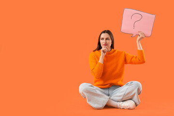 Thoughtful young woman holding speech bubble with question mark on orange background