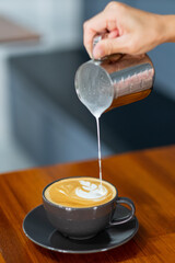 closeup hand doing hot latte art coffee