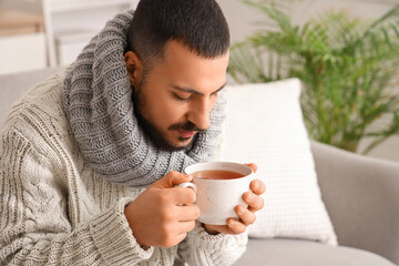 Ill young man with lemon tea at home, closeup