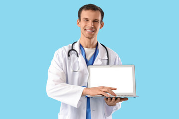 Male doctor using blank laptop on blue background