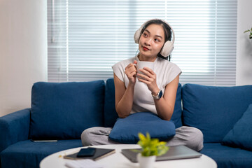 A woman is sitting on a blue couch with a cup in her hand
