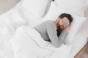 Morning of handsome man with mask sleeping in bedroom, top view