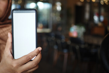 A Person Holding a Smartphone While Sitting in a Cafe Setting Enjoying Time